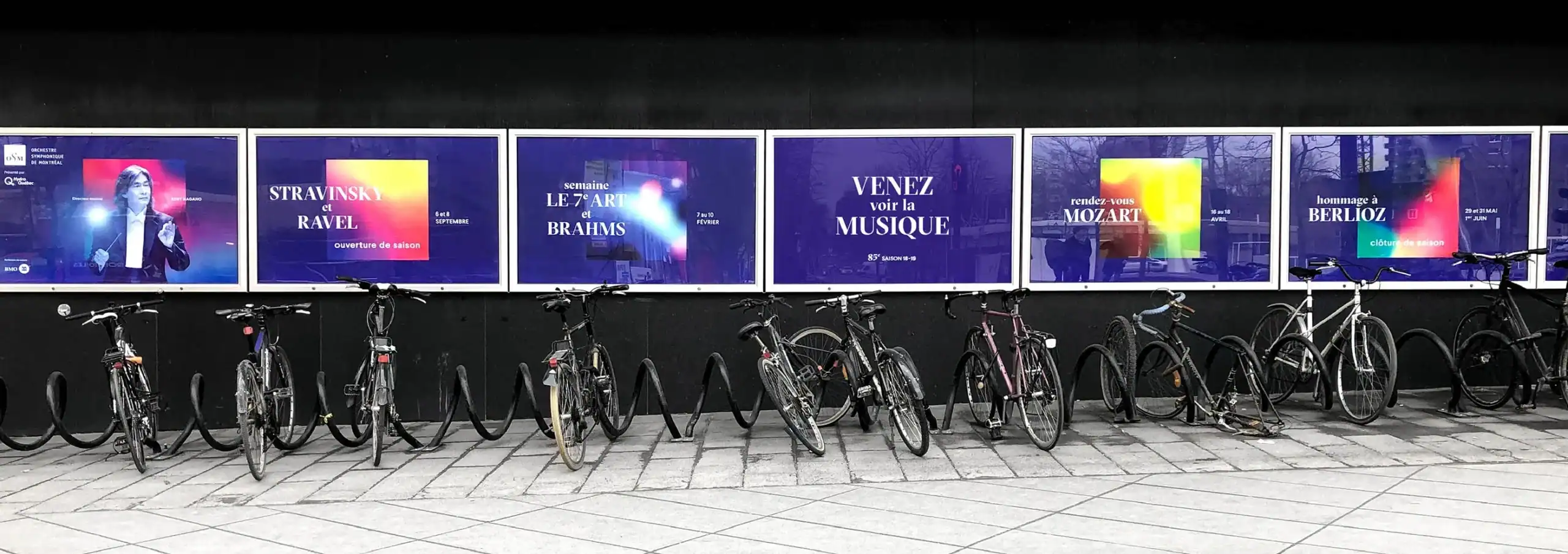 Modern synesthesia-inspired art display with digital screens and bicycles outside.